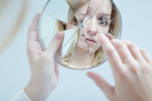 mulher olhando no espelho quebrado 1