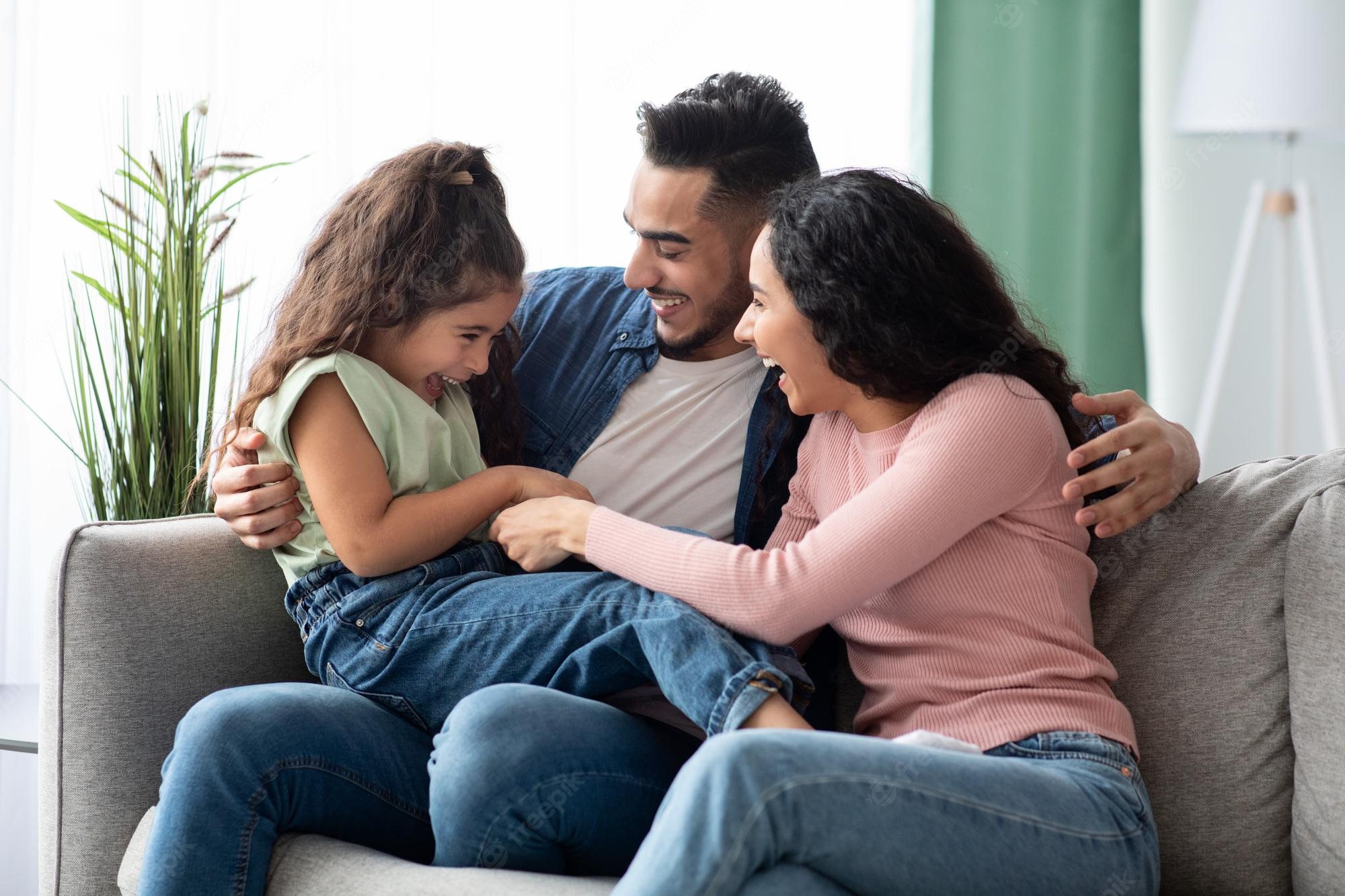 cheerful arabic family three having fun home middle eastern parents tickling their little daughter laughing together while relaxing couch living room free space 568137 894